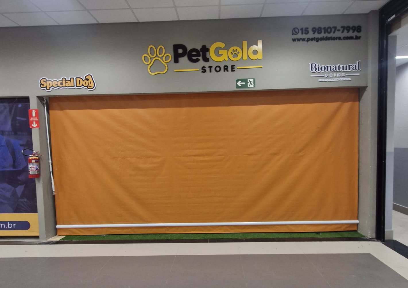 Toldo cortina laranja instalado em fachada comercial