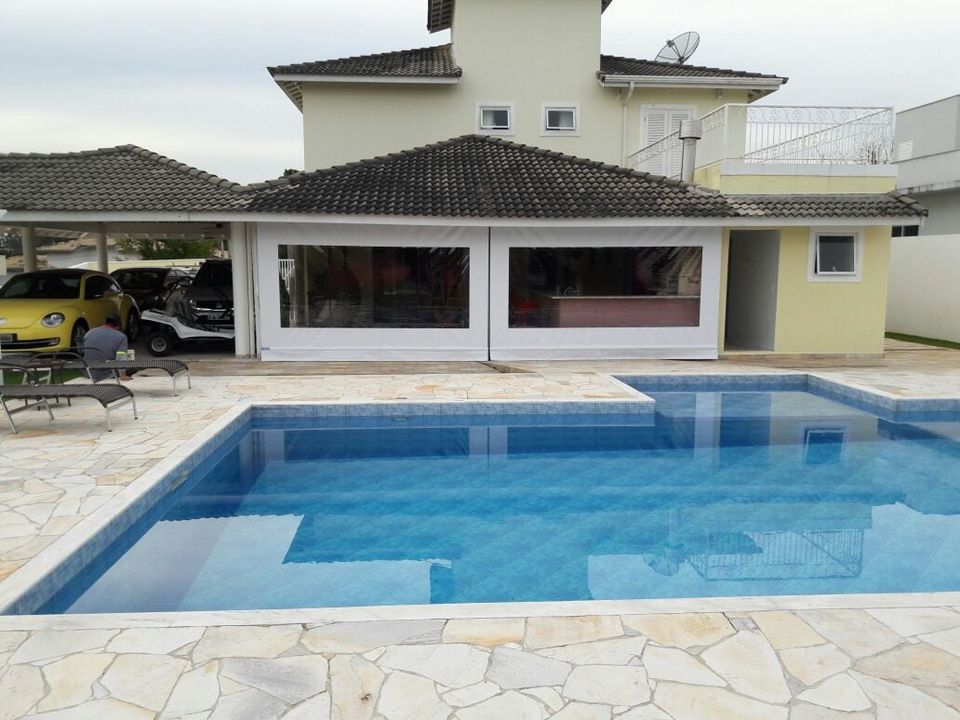 Toldo cortina branco instalado em área de piscina residencial