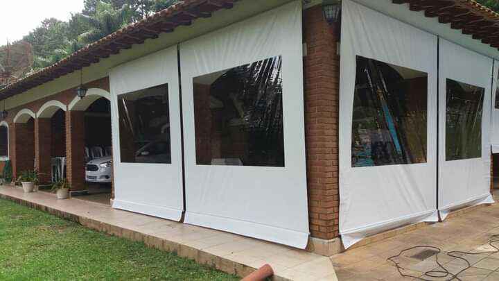 Fachada de residência com vários vãos fechados por toldo cortina branco com visores cristal
